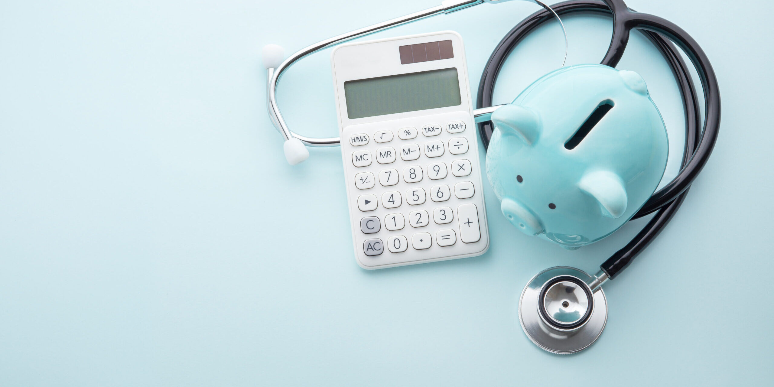 Piggy,Bank,With,Stethoscope,And,Calculator,On,Blue,Background,,Top