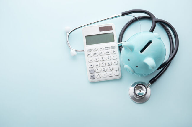 Piggy,Bank,With,Stethoscope,And,Calculator,On,Blue,Background,,Top