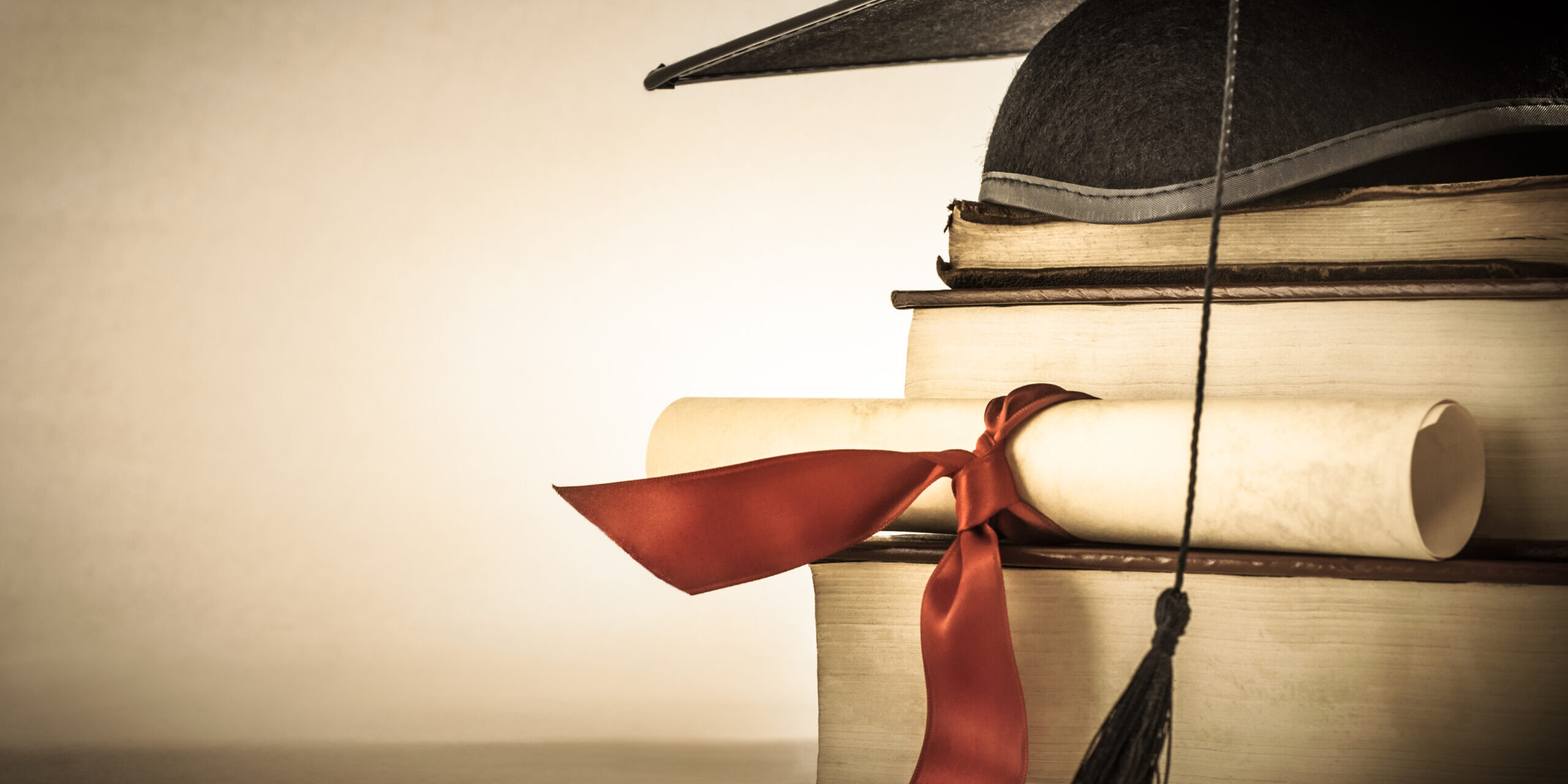 A,Mortarboard,And,Graduation,Scroll,,Tied,With,Red,Ribbon,,On