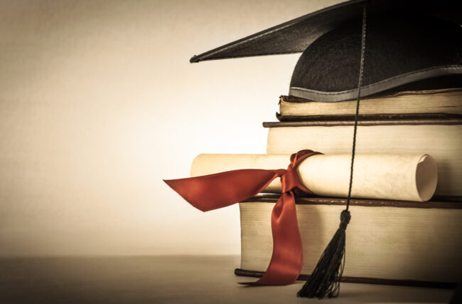 A,Mortarboard,And,Graduation,Scroll,,Tied,With,Red,Ribbon,,On