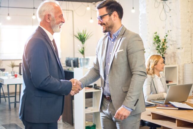 Senior,Executive,Shaking,Hands,With,Young,Employee,At,Office.